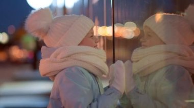 Hediyeler kutusuyla portre çocuk geleneksel Noel pazarında Noel vitrininde alışveriş yapıyor ve hayal kuruyor. Xmas Çocukluk Tatili Konseptini Sunar.
