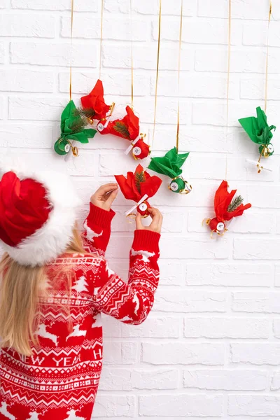 Child girl opening small gifts surprises advent calendar hanging on the wall. Happy waiting Christmas and new year. — Stock Photo, Image