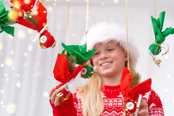 Barnflicka öppnar små gåvor överraskningar adventskalender hängande på väggen. Glad väntan Jul och nytt år. — Stockfoto