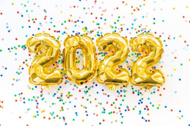 Mutlu yıllar 2022 kutlamaları. 2022 sayılı altın ve gümüş folyo balonlar ve pembe arka planda konfeti. Noel yatağı