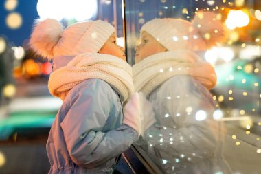 Portre Çocuk geleneksel Noel pazarında Noel vitrininde alışveriş yapıyor ve hayal kuruyor. Xmas Çocukluk Tatili Konseptini Sunar.