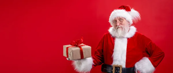 Baner naprawdę zabawny Święty Mikołaj z prezent pudełko na rękę na czerwonym tle studio. Wyprzedaż, rabat, Czarny Piątek. Przestrzeń chroniona — Zdjęcie stockowe