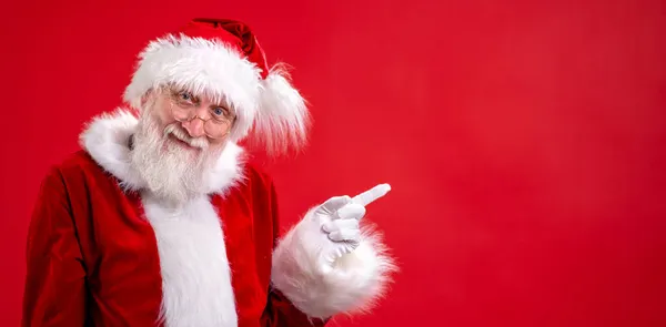 Banner-Weihnachtsmann zeigt auf leeren Kopierplatz am Finger und zeigt leeren Platz für beworbenes Produkt oder Text auf rotem Studiohintergrund. Sale, Discount, Black Friday. Sehen Sie sich das an. — Stockfoto