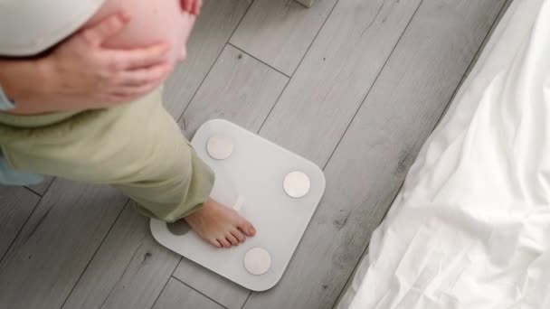 Młoda kobieta mierzy ciężarną wagę stojąc na wadze. Przygotowanie do porodu, Dziewczyna duży brzuch zaawansowane zdrowej ciąży — Wideo stockowe