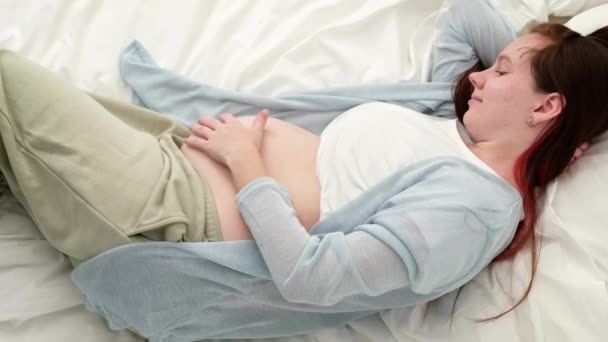 Top view Zwangere aanstaande moeder streelt haar buik. Vrouw handen aanraken van haar buik, wachtend kind, liggend op bed Voorbereiding voor de bevalling, Meisje grote buik gevorderde zwangerschap — Stockvideo