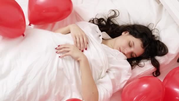 Brunetka Europejska dziewczyna śpi na łóżku z czerwonym kształcie serca.Poranek prezent niespodzianka na Walentynki — Wideo stockowe