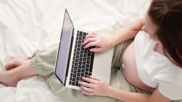 4k Top view Várandós anya dolgozik távolról online otthonról. Közelkép terhes fiatal nő kezét laptop nagy has előrehaladott terhesség 14.05.21 StPetersburg Oroszország. — Stock videók