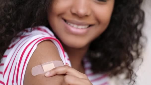 Geimpfte Afroamerikanerin zeigt Arm mit medizinischem Pflaster Gips auf der Schulter, schwarze Frau nach Erhalt der Impfdosis gegen Covid. Impfungen im Gesundheitswesen, Coronavirus-Impfungen. — Stockvideo
