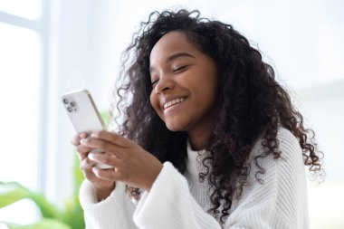 iPhone 12 kullanan Afro-Amerikan Kızı akıllı telefon basıyor, sosyal medya interneti okuyor, iki siyah el 13.12.21 St. Petersburg Rusya 'sında metin veya online alışveriş yapıyor.