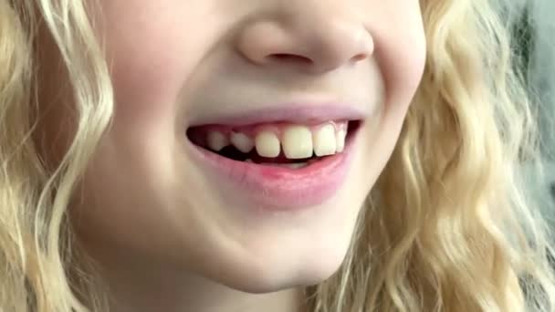 Блондинка кавказская девочка, трясущая языком молочный зуб во рту, детская стоматология стоматология и потеря первого премоляра. — стоковое видео