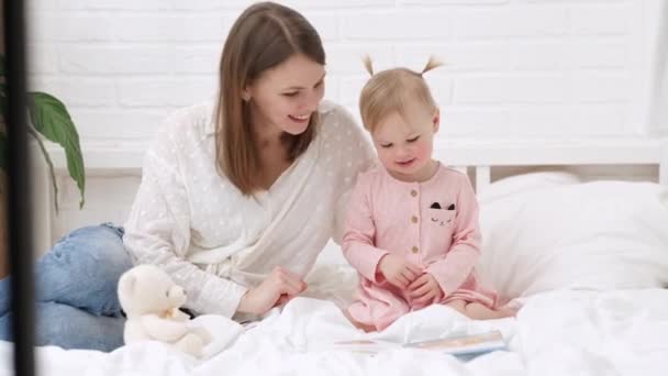 Mor och barn läser en bok i sängen innan de somnar. Familjen älskar tid tillsammans — Stockvideo