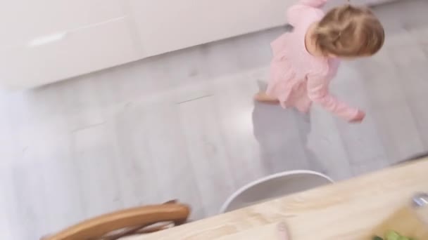 Little cute 2 lat dziewczyna bawiąc bieganie wokół stołu kuchennego zamiast jedzenia, Problemy, jak karmić dziecko. Widok z góry — Wideo stockowe