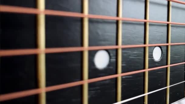 ズームで黒のフリートボードのアコースティックギターの文字列のショット — ストック動画