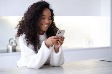 iPhone 12 kullanan Afro-Amerikan Kızı akıllı telefon basıyor, sosyal medya interneti okuyor, iki siyah el 13.12.21 St. Petersburg Rusya 'sında metin veya online alışveriş yapıyor.
