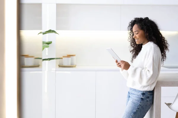 African American Girl usando la tableta iPad en casa presionando el dedo, leyendo las redes sociales de Internet, escribiendo texto o comprando en línea. Freelancer Trabajar de forma remota en línea en casa. Fotos De Stock