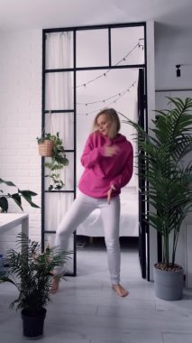 Neşeli heyecanlı milenyum kızı oturma odasında müzik dinlerken eğleniyor çılgın dansta mutlu genç bir kadın evde eğlenceli bir hafta sonu geçiriyor, stresten uzak bir konsept. Dikey görüntüler.