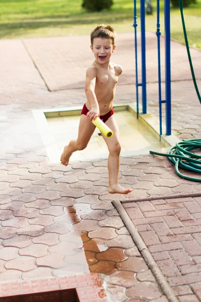 Enfant courant avec canon à eau — Photo