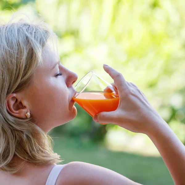 Mujer rubia beber jugo multivitamínico — Foto de Stock