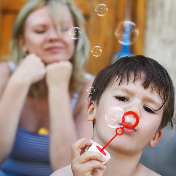 Мальчик надувает мыльные пузыри — стоковое фото