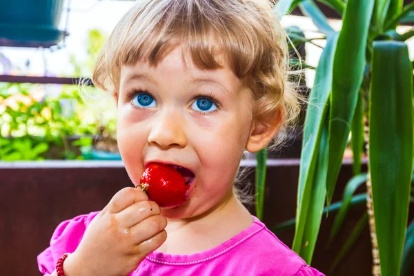 Klein meisje eten tomaat — Stockfoto