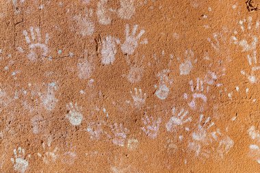 Çocukların tebeşirle oynaması, palmiyelerin toz rengi, kaba duvar cephesindeki el izleri, çocukluk tasarımı.