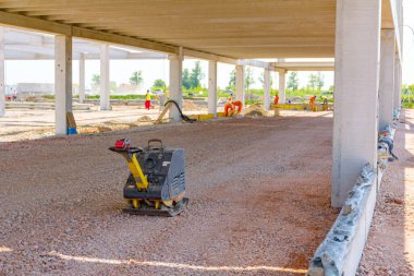 Kullanılmış plaka kompaktörü, titreşimli çekiç, atlama jakı makinesi, şantiyede gölgede yerleştirilen elektrikli alet.