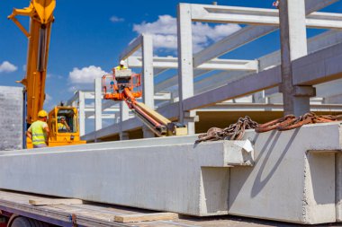 Kargo kamyonu kargoyu boşaltıyor beton inşaat alanı inşaatı için beton kiriş. Turna kancası, beton kirişe bağlanma mekanizması