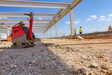Kullanılmış plaka kompaktörü, titreşimli çekiç, atlama jakı makinesi, şantiyede gölgede yerleştirilen elektrikli alet.