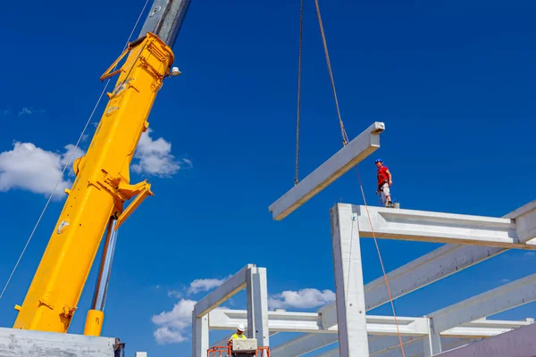 İşçi için derleme büyük inşaat beton kiriş yönetmek için Mobil vinç yardım ediyor.