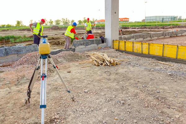 Total center device on tripod with laser for leveling other devices to level construction site.
