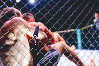 Radyo için profesyonel mikrofon, canlı yayın MMA dövüşü, dövüşçüler sıkı sıkıya sarıldı, sekizgen katta parterre güreşi yapıyorlar..