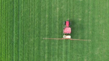 Tepede, tepedeki kule, traktörü tarla üzerine monte edilmiş taze yeşil buğday püskürten tarla püskürtücüsü olarak hareket ettiriyor..