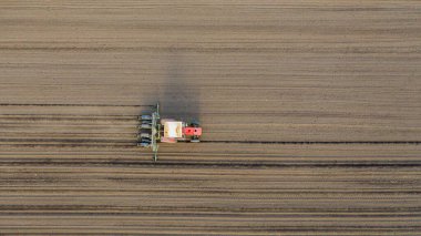 Üstten bakıldığında, traktörün tarla, toprak, yeni tahıl, mısır, mısır ekimi üzerine mekanik tohum ekme makinesi çekmesi..