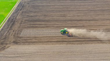 Çekme makinesi olarak traktörün üstünde, tarlaları yıpratan, gelecek sezon ekin ekimi için toprağı hazırlayan. Toz bulutu arkamızda uçuyor.