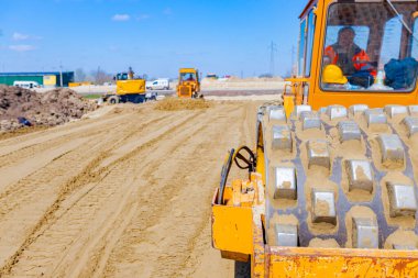 Vibratörlü yol silindirini görüntüle, dikenler titreşiyor, sıkıştırıcı sıkıştırıyor, inşaat alanındaki yol temeli için kumu dolduruyor.