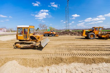 Çivili yol silindiri, buldozer ve kamyon plaka sıkıştırıcı ile sıkıştırılıyor, inşaat alanındaki yol temeli için kumu düzleştiriyor.