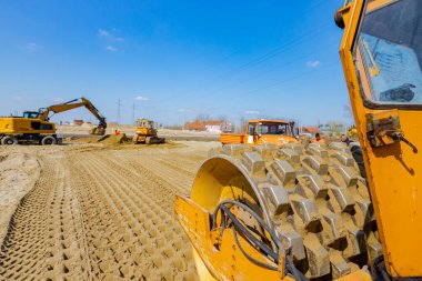 Vibratörlü yol silindirini görüntüle, dikenler titreşiyor, sıkıştırıcı sıkıştırıyor, inşaat alanındaki yol temeli için kumu dolduruyor.