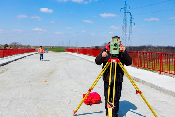 測量士のエンジニアは 建設中の橋 サイトを測定しています 測量士は 大規模な建設プロジェクトを実施する前に正確な測定を保証 — ストック写真