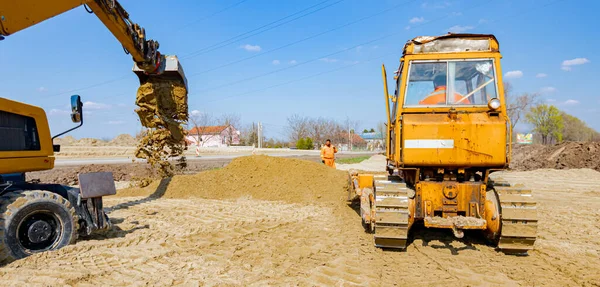 建設現場で道路基盤のための砂を平準化しているブルドーザーや掘削機の後ろからの眺め 機械化 — ストック写真