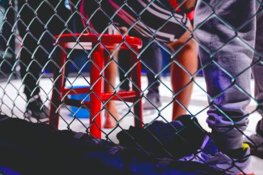 Kavgalar arasında dinlenen dövüşçüler için kırmızı boksör koltuğundaki dövüş halkasının içinden bakın..