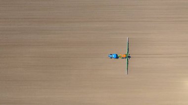 Üst manzaranın üstünde, traktörün üzerinden... uçsuz bucaksız tarlaları püskürtene kadar... ekilmiş tarımsal bir tarlaya... monte edilmiş geniş tarım püskürtücüsünü sürükleyene kadar..