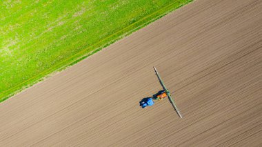 Üst manzaranın üstünde, traktörün üzerinden... uçsuz bucaksız tarlaları püskürtene kadar... ekilmiş tarımsal bir tarlaya... monte edilmiş geniş tarım püskürtücüsünü sürükleyene kadar..