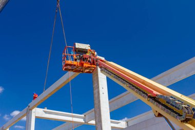 Vinçler-Mobil vinç işletim ve derleme beton kiriş yüksek yerde çalışıyor. Yükseklik işçi iskelet bina truss çiziyor.