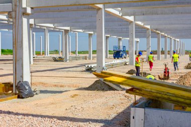 Yığılmış, boyanmış, ahşap tahtalar inşaat alanındaki kamyon karavanına yerleştiriliyor. Riggers ve işçiler somutlaştırma için uzun kalıplar oluşturuyorlar.