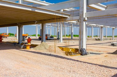 Beton kirişler, insanların çalıştığı devasa bir yapının tamamlanmamış iskeleti haline getirilir. İnşaat alanından görüntüle.
