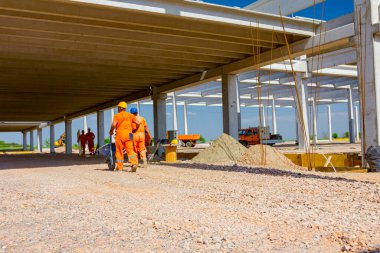 Beton kirişler, insanların çalıştığı devasa bir yapının tamamlanmamış iskeleti haline getirilir. İnşaat alanından görüntüle.