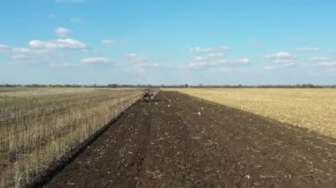 Traktör, ekilebilir alanı yıpratan ve toprağı gelecek sezon için hazırlayan bir disk dişli makineyi çekiyor. Aç kuş sürüsü, beyaz martılar yiyecek aramak için tarımsal makineyi takip ediyor..