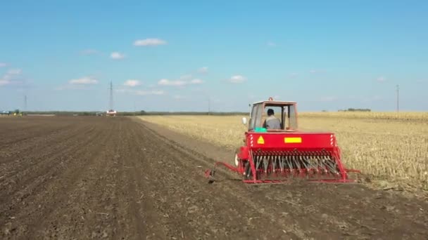 耕作可能なフィールド 新しい小麦作物を植える上に種子ドリルマシンを引っ張るトラクターのドーリー移動ショット — ストック動画
