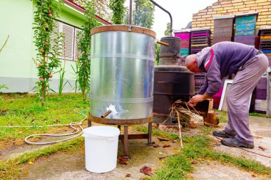 Adam, kaçak içki ve alkollü içecekler yapan ev yapımı bir içki imalathanesinin şömine rafına kuru dallar atıyor..