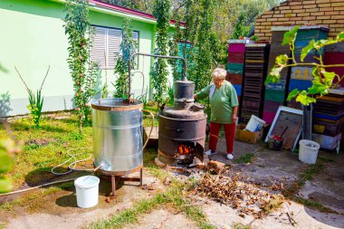 Kadın, el ile bakırdan yapılmış el yapımı içki imalathanesinde meyve markı karıştırmak, kaçak içki, brendi, konyak, viski, viski, viski, viski, cin, viski gibi alkollü içecekler yapmak için kolu çeviriyor..